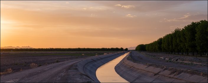 Panoramic view of a serene Texan sunset captured in Fabens, showcasing a vast rural landscape and an expansive horizon bathed in soft blended gradients, evoking tranquility as the day transitions into night.