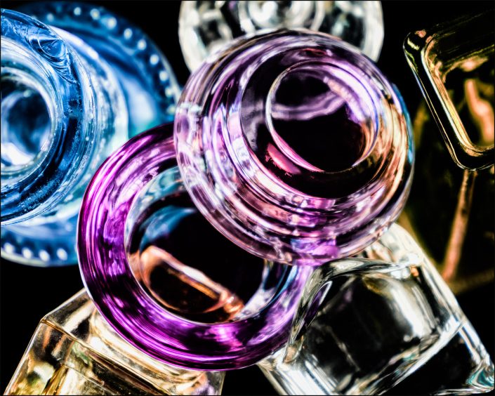 Second abstract fine art photo from the ten-image series, "An Abyss of Glass & Color" which features vivid colors, highlights, and shadows on various layered glass objects. Captured from below, the image creates a sense of depth from the layered space by blending form, light, and color to evoke a vibrant, infinite void.
