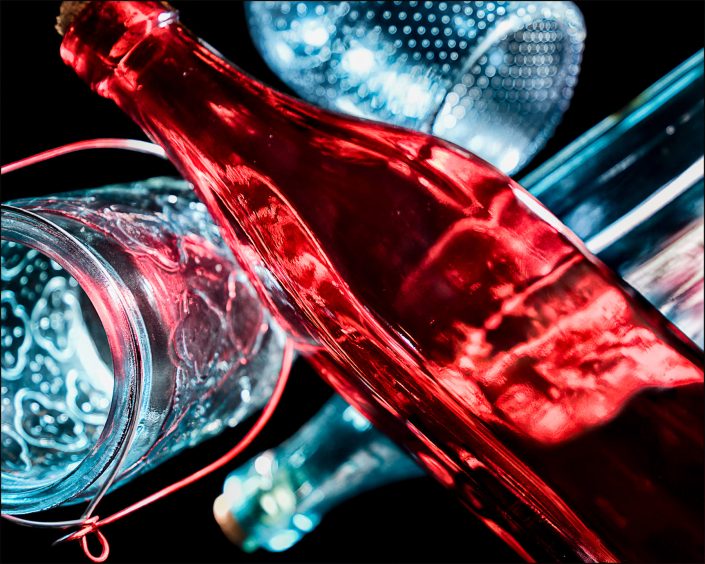 Eighth abstract fine art photo from the ten-image series, "An Abyss of Glass & Color" which features vivid colors, highlights, and shadows on various layered glass objects. Captured from below, the image creates a sense of depth from the layered space by blending form, light, and color to evoke a vibrant, infinite void.