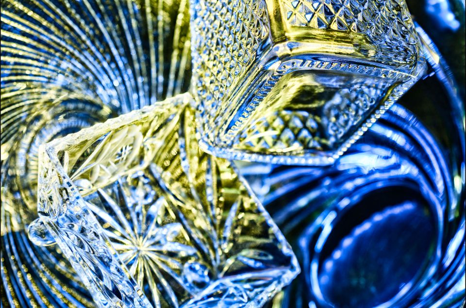 Ninth abstract fine art photo from the ten-image series, "An Abyss of Glass & Color" which features vivid colors, highlights, and shadows on various layered glass objects. Captured from below, the image creates a sense of depth from the layered space by blending form, light, and color to evoke a vibrant, infinite void.