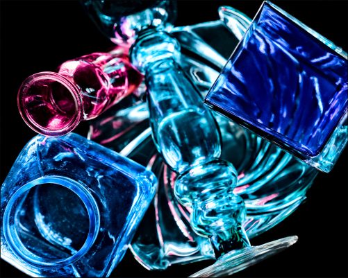 Fifth abstract fine art photo from the ten-image series, "An Abyss of Glass & Color" which features vivid colors, highlights, and shadows on various layered glass objects. Captured from below, the image creates a sense of depth from the layered space by blending form, light, and color to evoke a vibrant, infinite void.