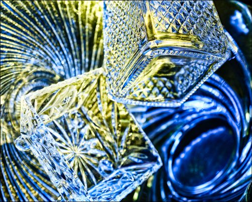 Ninth abstract fine art photo from the ten-image series, "An Abyss of Glass & Color" which features vivid colors, highlights, and shadows on various layered glass objects. Captured from below, the image creates a sense of depth from the layered space by blending form, light, and color to evoke a vibrant, infinite void.